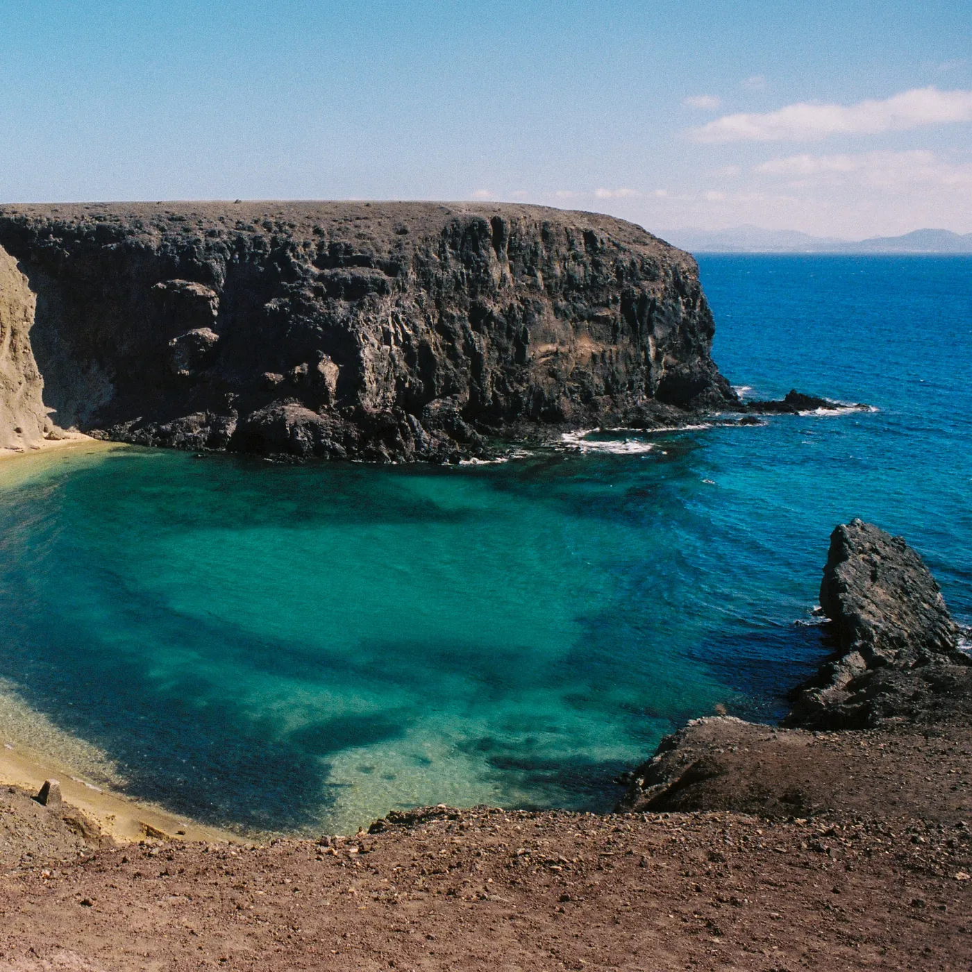 火山岩の断崖のそばに広がるターコイズブルーの入り江(JLP公式のスピルリナ紹介ページの画像)